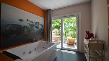 Une salle de bain moderne avec une grande baignoire, un meuble-lavabo en bois et une porte coulissante en verre donnant sur un patio.