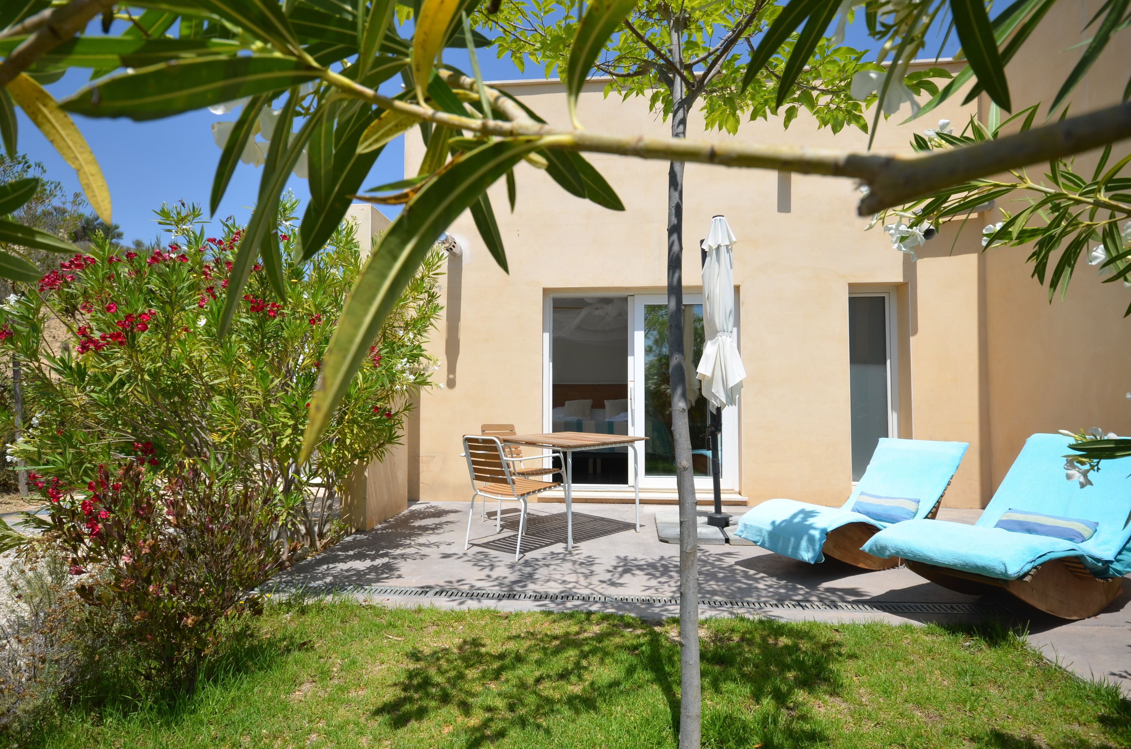 Un patio con tavolo e sedie, un ombrellone e due poltrone da relax.