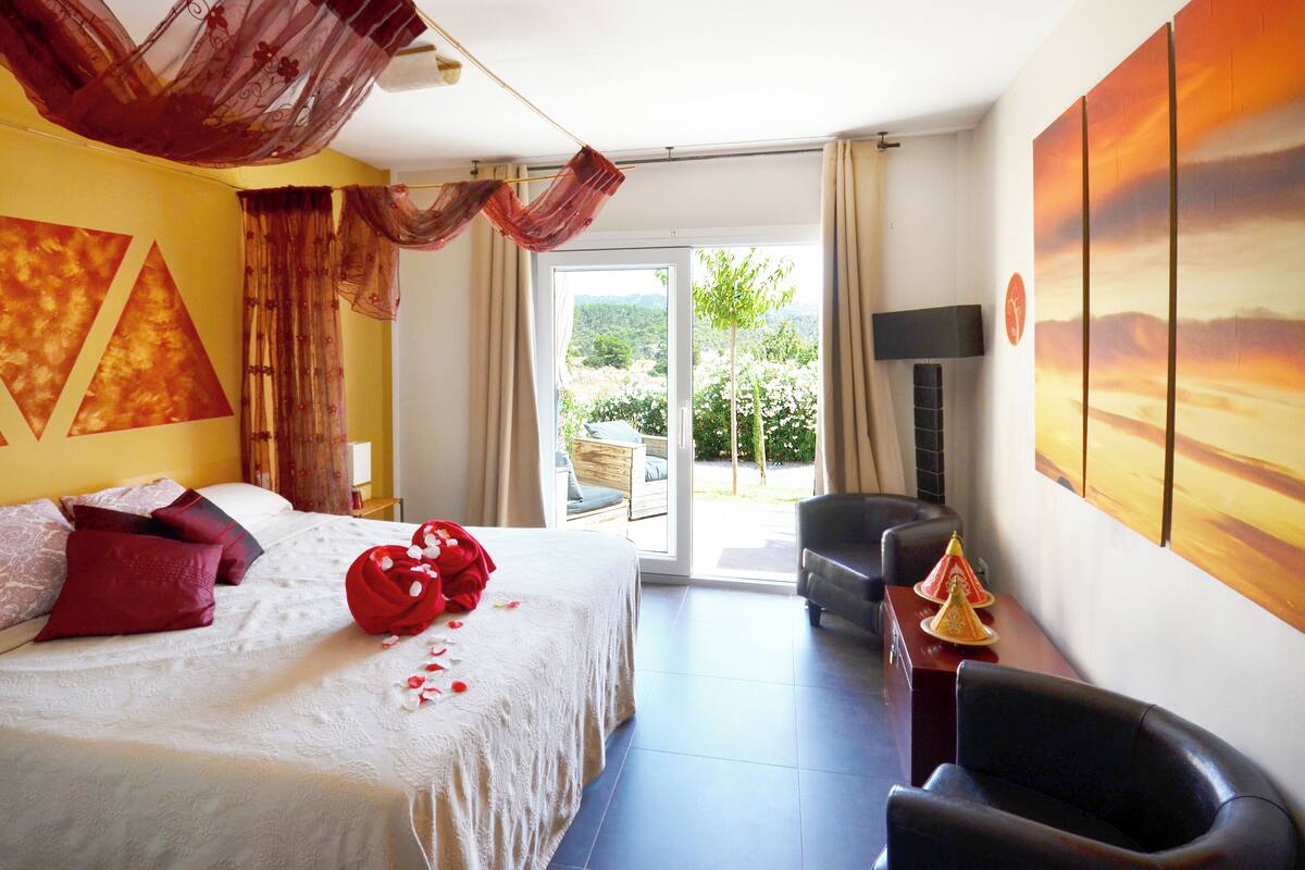 A hotel room with a bed, a desk, a chair, and a view of the outdoors.