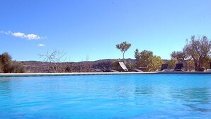 A clear blue pool with a view of a beach and trees in the background. - El Pao  (Jijona)