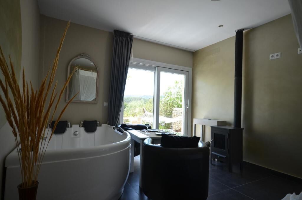 Un baño moderno con una bañera grande, un espejo y una ventana con vistas a la vegetación.