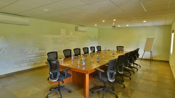 Un salón de conferencias con una larga mesa, varias sillas y una pizarra.