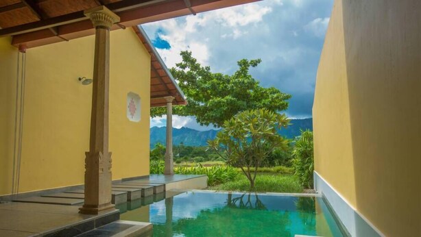 A pool area with a view of mountains and greenery. - Dvara Siruvani (Coimbatore)