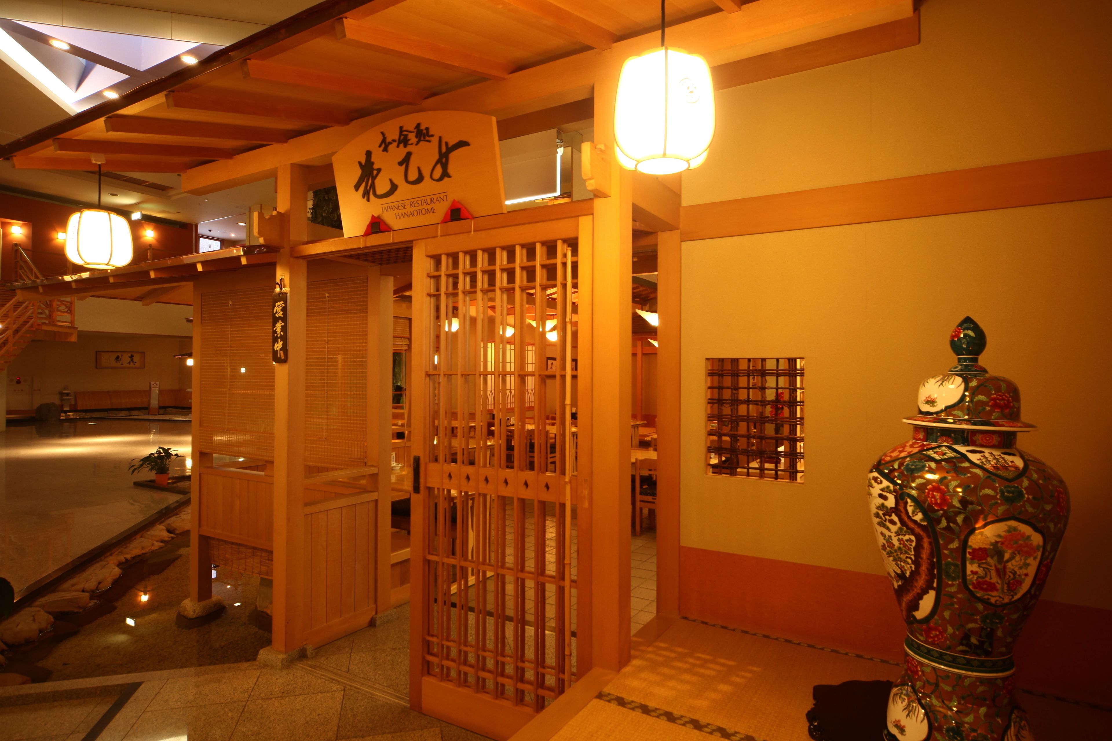 Interior de un restaurante japonés tradicional con puertas correderas de madera, un jarrón decorativo y un letrero que indica que es un restaurante japonés.