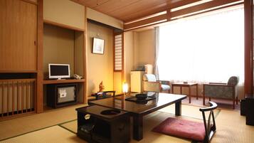 Een traditionele Japanse kamer met tatami vloerbedekking, een lage tafel, een bank en een televisie.