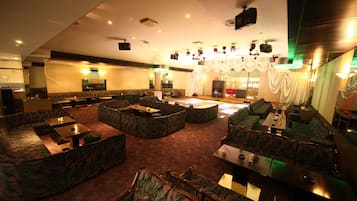 A spacious lounge area with multiple seating options including sofas and armchairs, arranged around a central coffee table.