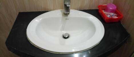 A white sink with a single faucet on a black countertop.