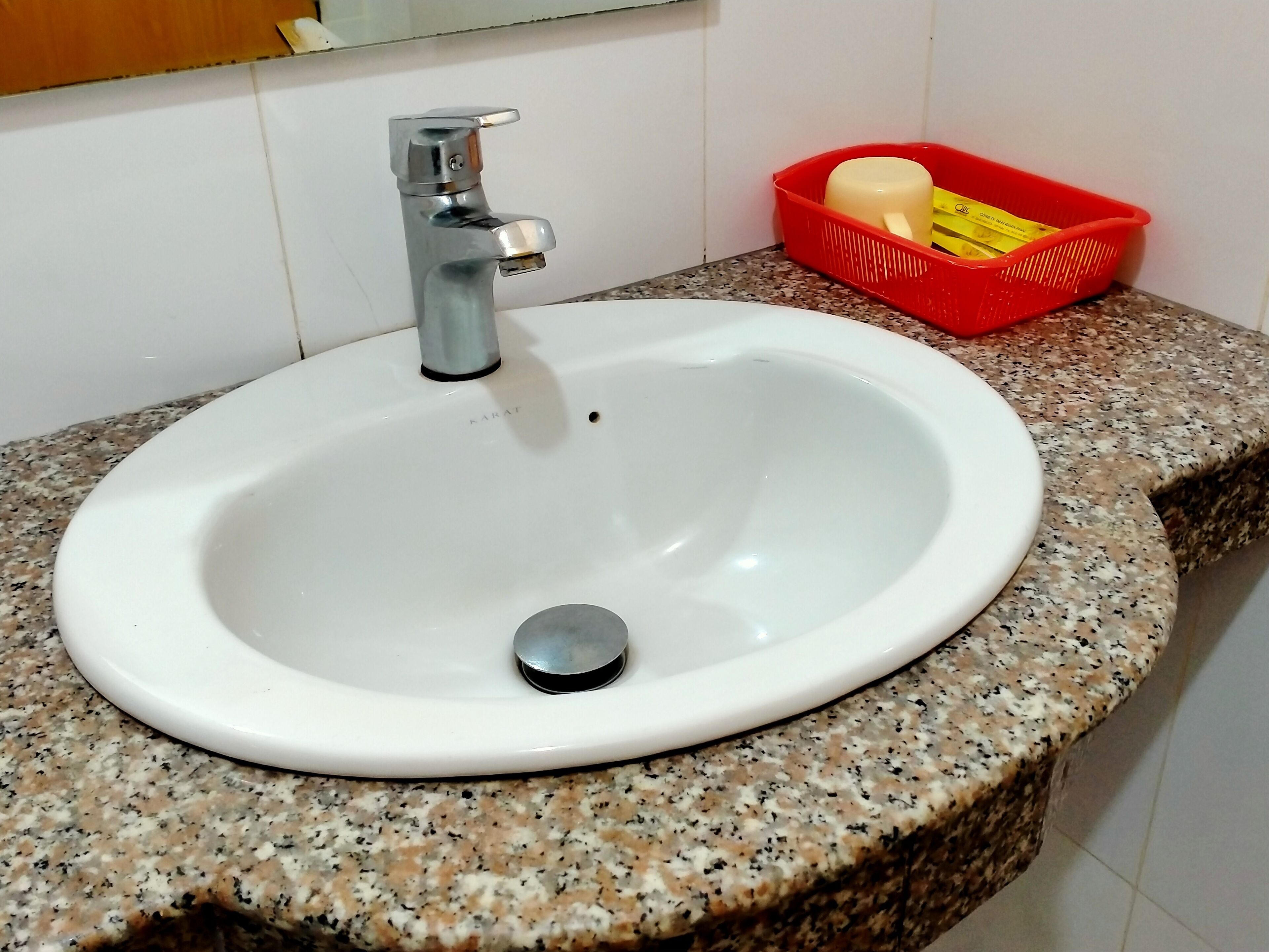 A white sink with a chrome faucet on a granite countertop.