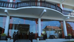 A hotel with a curved balcony, large glass windows, and a well-maintained entrance area. - Hotel Sanmark (Ahangama)