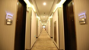 A hotel hallway with carpeted floors, wooden doors, and illuminated room numbers. - Crown Crystal Hotel (Shanghai)