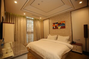 Quarto de hotel com cama, mesa de cabeceira e uma pequena escrivaninha com cadeira.