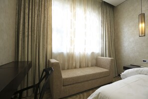 A hotel room with a sofa, a desk, and a bed. - Crown Crystal Hotel (Shanghai)