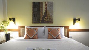 A hotel room with a bed, pillows, a wall art piece, and two wall-mounted lamps. - iRest Ao Nang Seafront (Krabi)