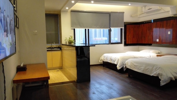 A compact hotel room with a kitchenette, two beds, a small table, and a view of the city through the window. - Cotton hotel (Chengdu)
