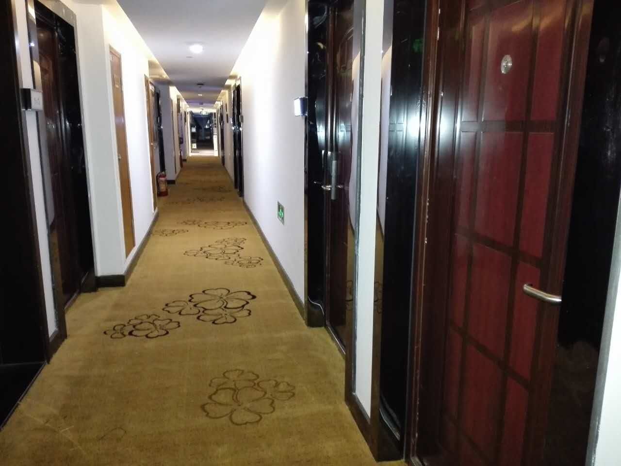 Un couloir d’hôtel avec des revêtements de sol en moquette et des portes de part et d’autre.