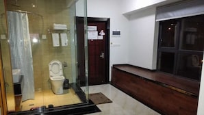 A modern bathroom with a glass shower enclosure, a toilet, and a bench. - Cotton hotel (Chengdu)