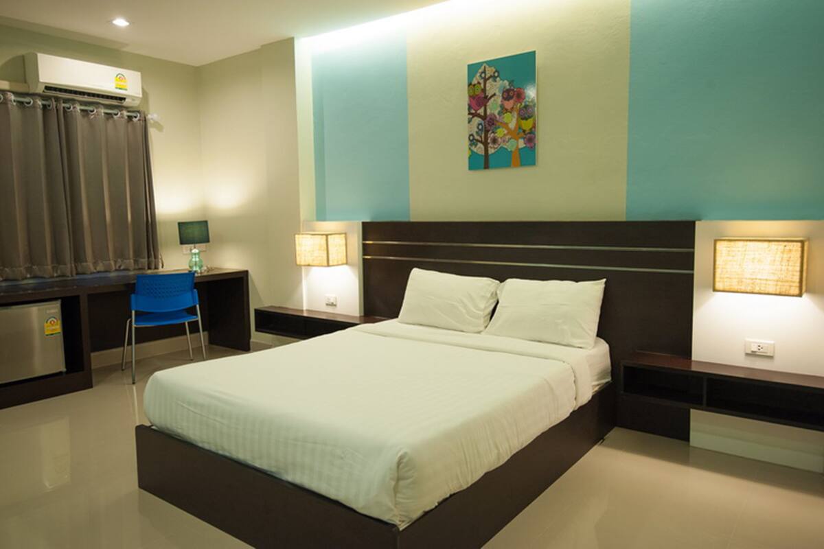 A hotel room with a bed, desk, chair, and two bedside lamps.