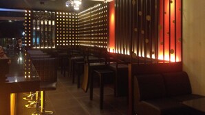 A modern interior with a bar area, seating, and a decorative wall with lights.