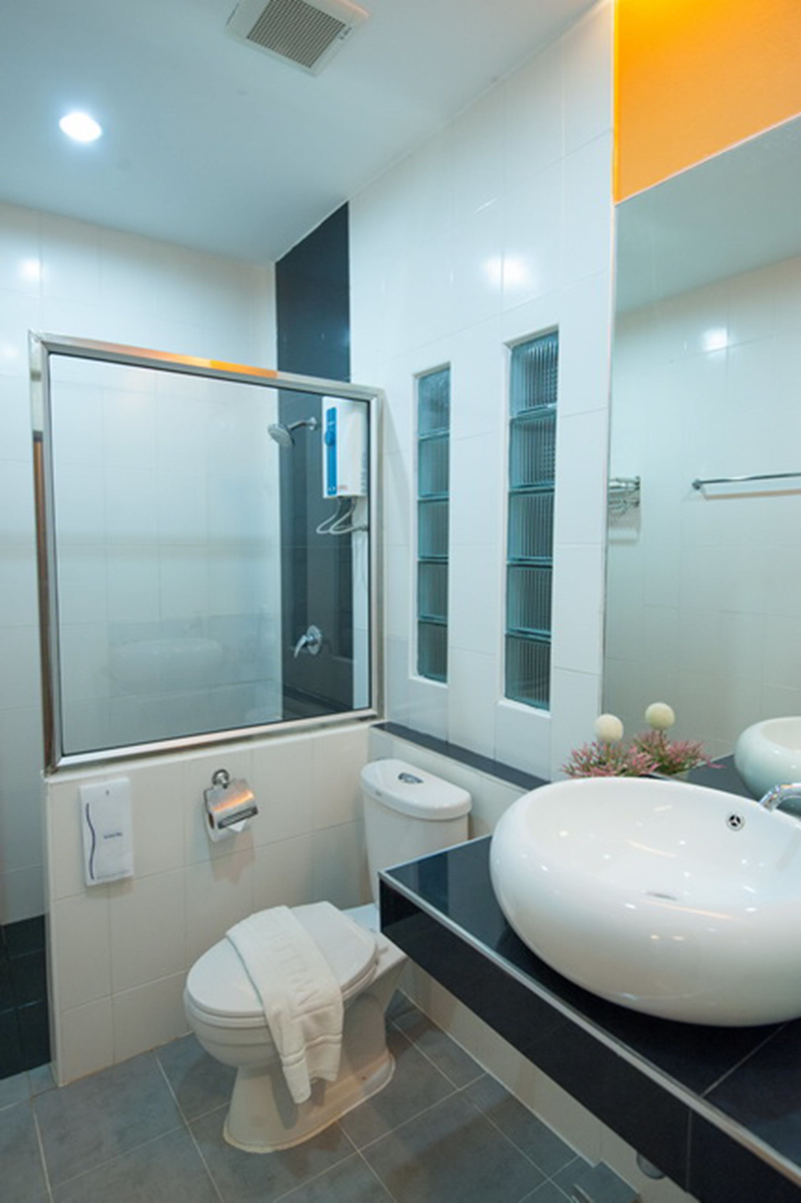Un baño moderno con ducha de vidrio, inodoro, lavamanos y espejo.
