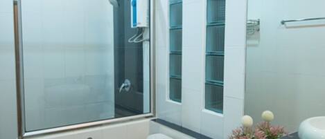 Un baño moderno con ducha de vidrio, inodoro, lavamanos y espejo.