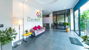 A modern hotel lobby with a colorful sofa, a reception desk, and a large window offering a view of the outdoors.