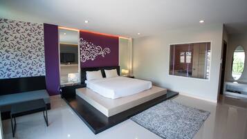 A modern bedroom with a large bed, a bench, a TV, and a decorative wall.