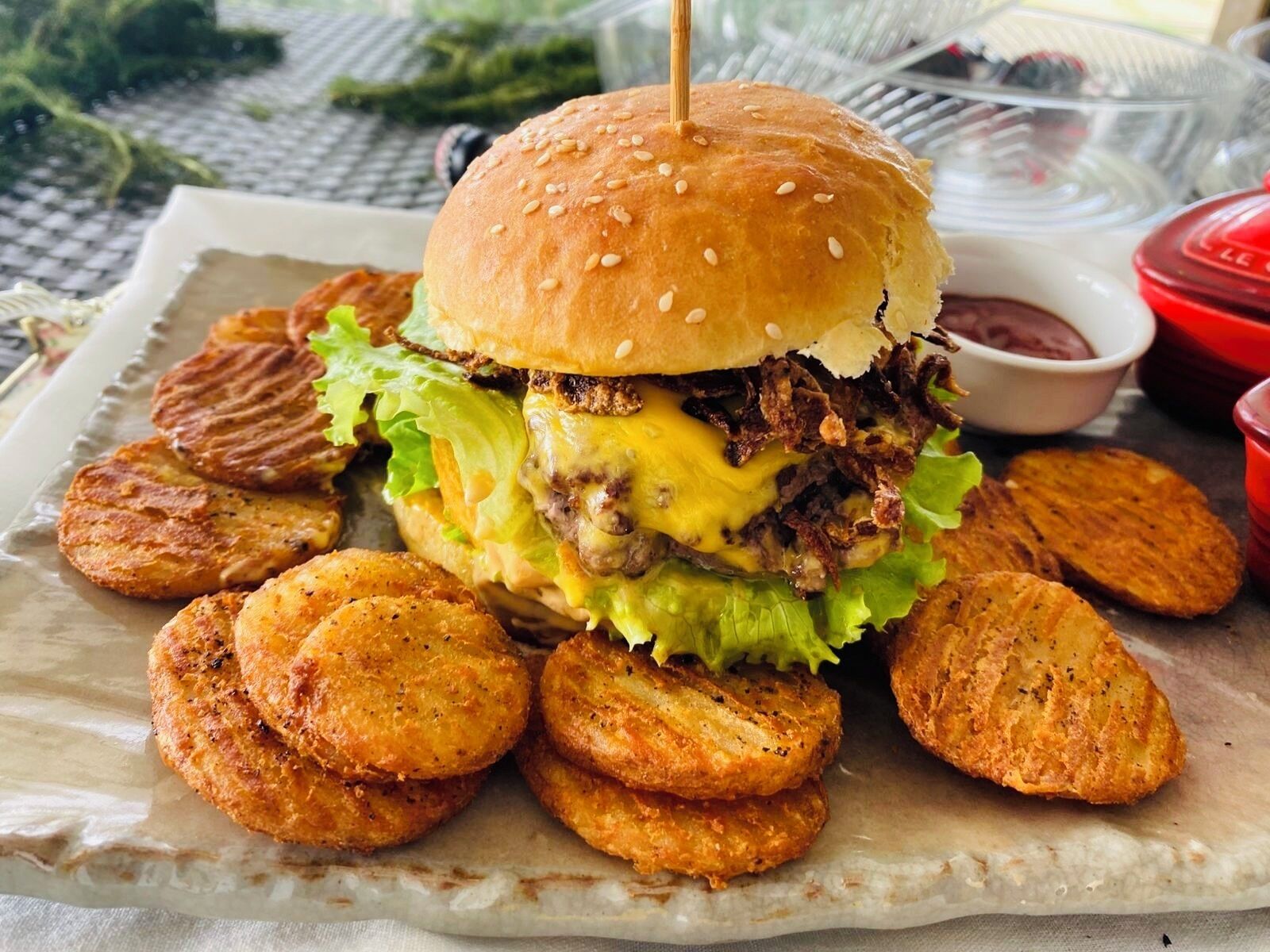A burger with fries and a drink on a plate.