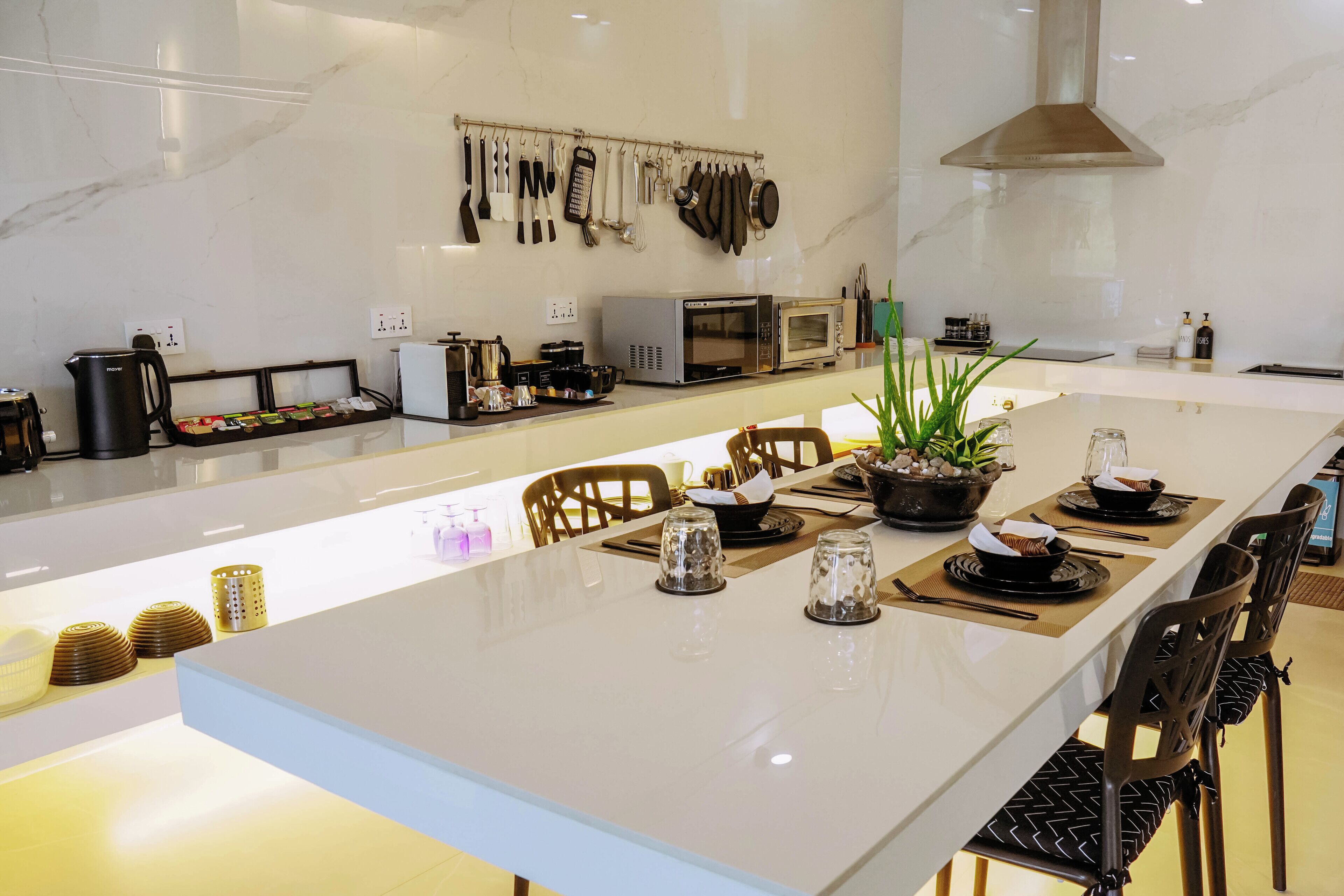 A modern kitchen with a long island, various appliances, and a hanging utensil rack.