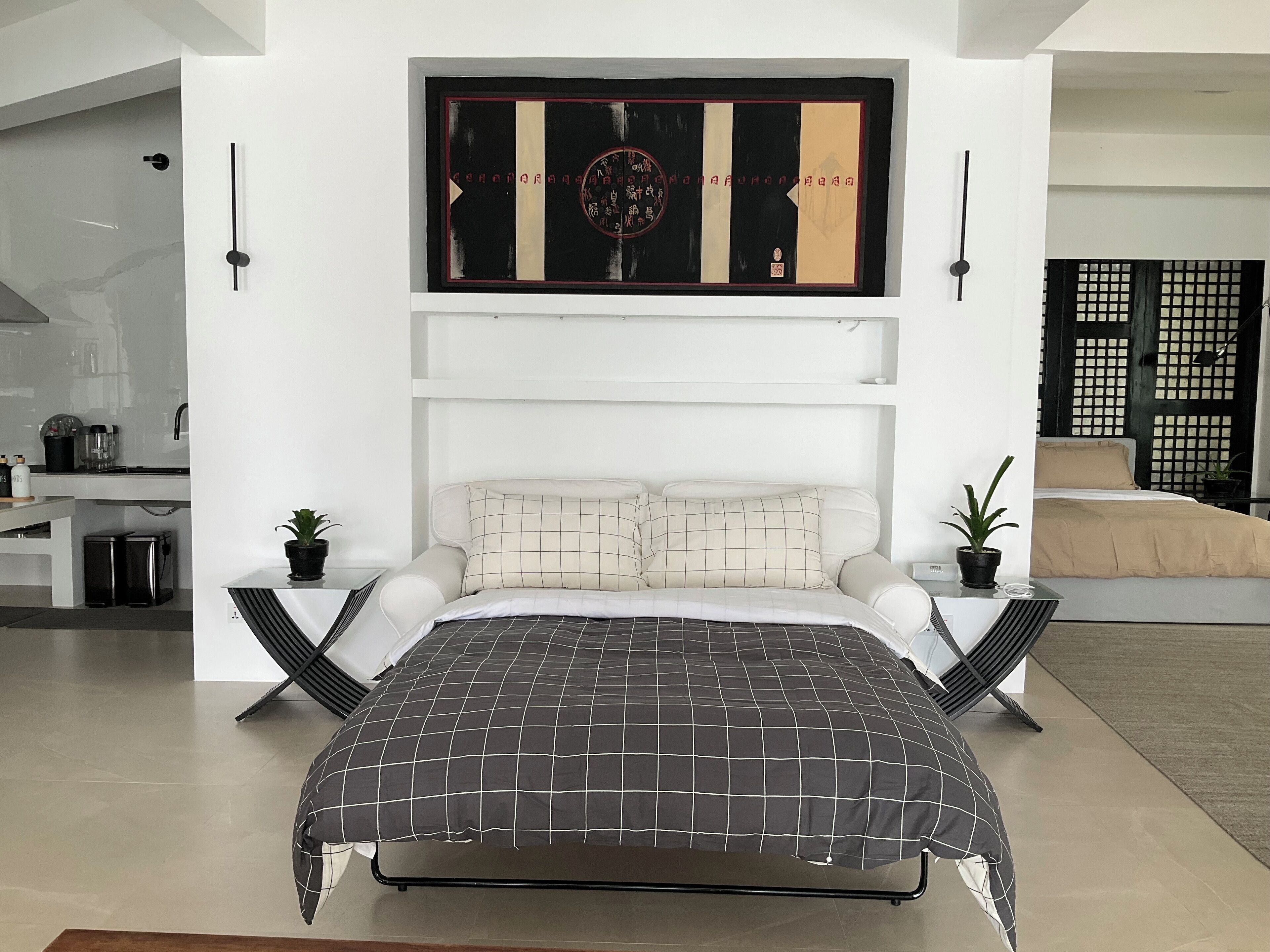 A modern bedroom with a large bed, a wall-mounted artwork, and a minimalist design.