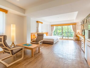 Una habitación de hotel con cama, escritorio, silla, mesa y balcón con vistas.