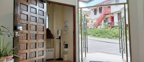 A hotel entrance with a wooden door and a glass door leading outside.