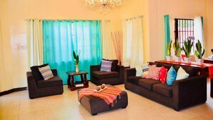 A living room with two sofas, a coffee table, and a chandelier. - Umaverde Bed & Breakfast (San Jose de Buenavista)
