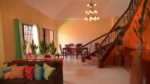 A spacious living room with a staircase, a dining area, and a sofa with colorful cushions. - Umaverde Bed & Breakfast (San Jose de Buenavista)