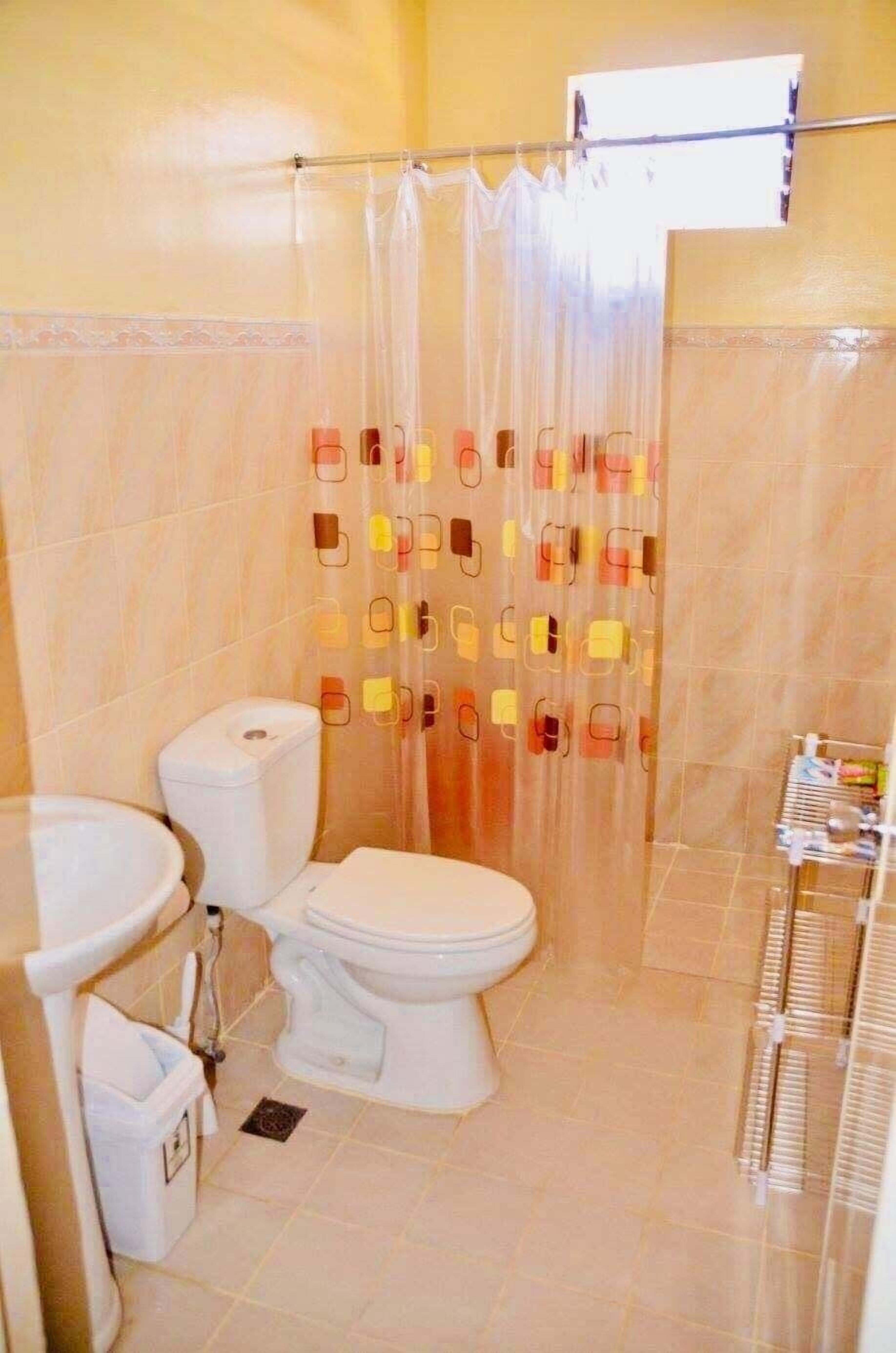 A bathroom with a toilet, bidet, and a shower curtain with a pattern.