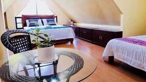 A cozy room with a glass table, two beds, a sofa, and a potted plant. - Umaverde Bed & Breakfast (San Jose de Buenavista)