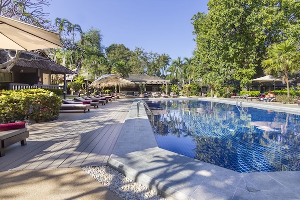 Una piscina al aire libre, sillones reclinables de piscina