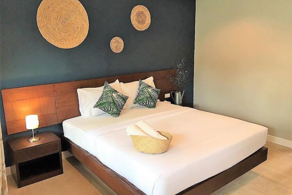 Una cama bien hecha con sábanas blancas, cabecera de madera y almohadas decorativas.