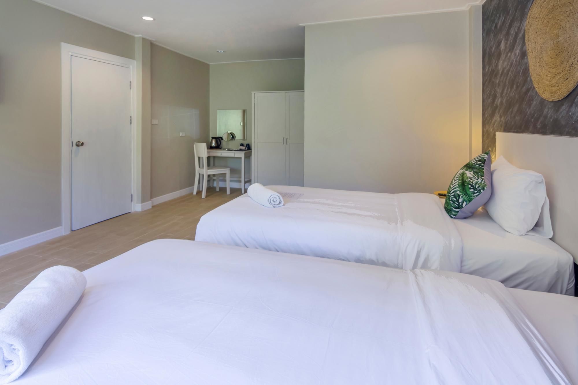 Ein Hotelzimmer mit zwei Betten, einem Schreibtisch und einem Stuhl.