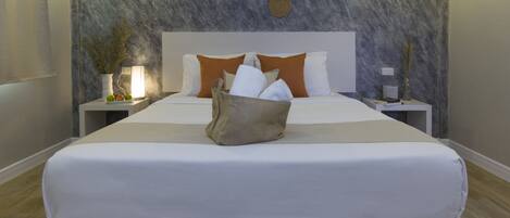 A neatly made bed with white linens, a bedside table with a lamp, and a wall with textured panels and decorative elements.