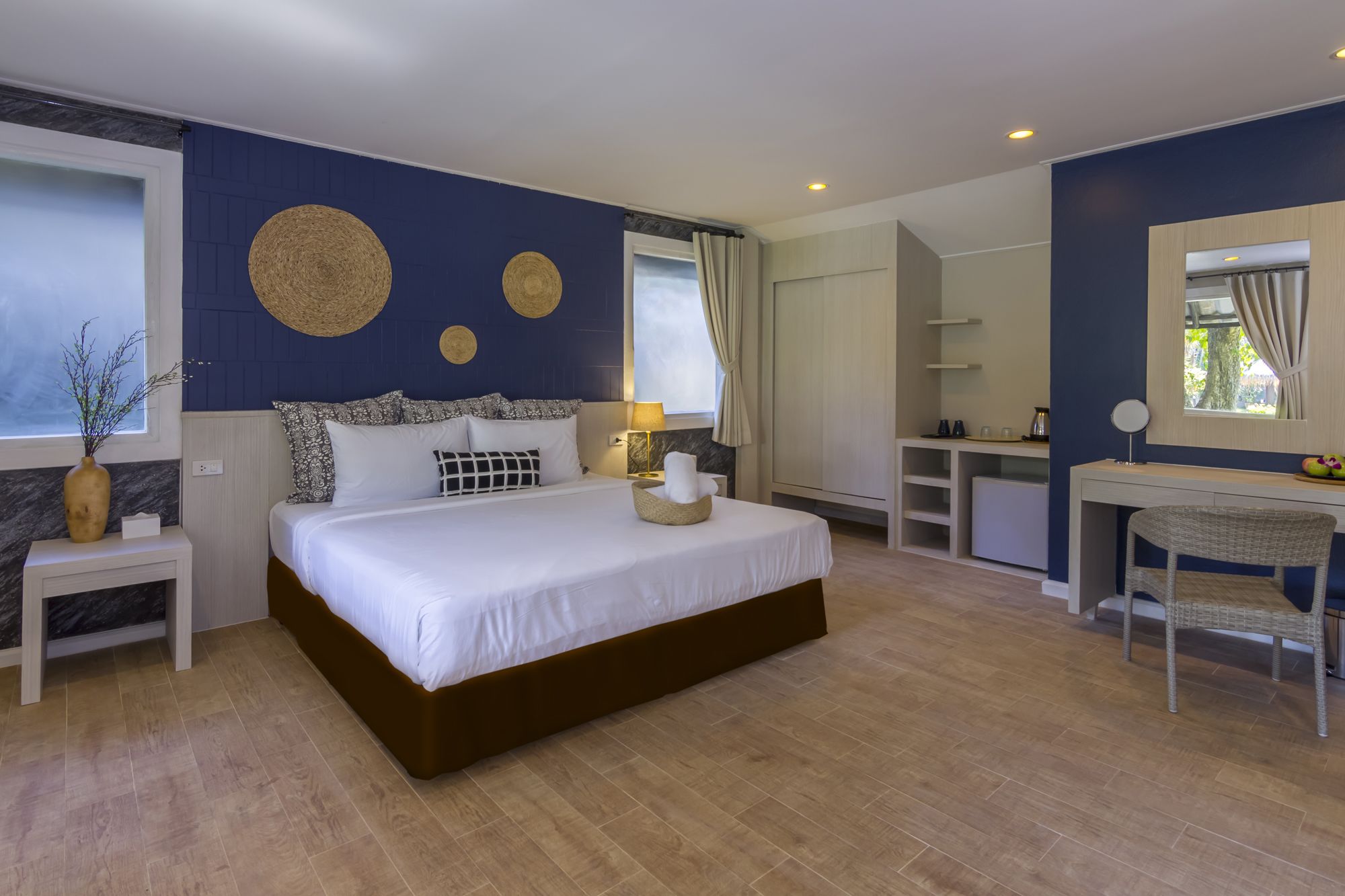 A modern bedroom with a large bed, bedside tables, a desk, and a chair.