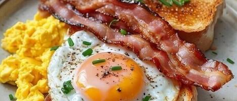 A breakfast plate with eggs, bacon, toast, and a glass of orange juice.
