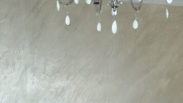 Un comedor con mesa y sillas de madera, pared de mármol y una araña.