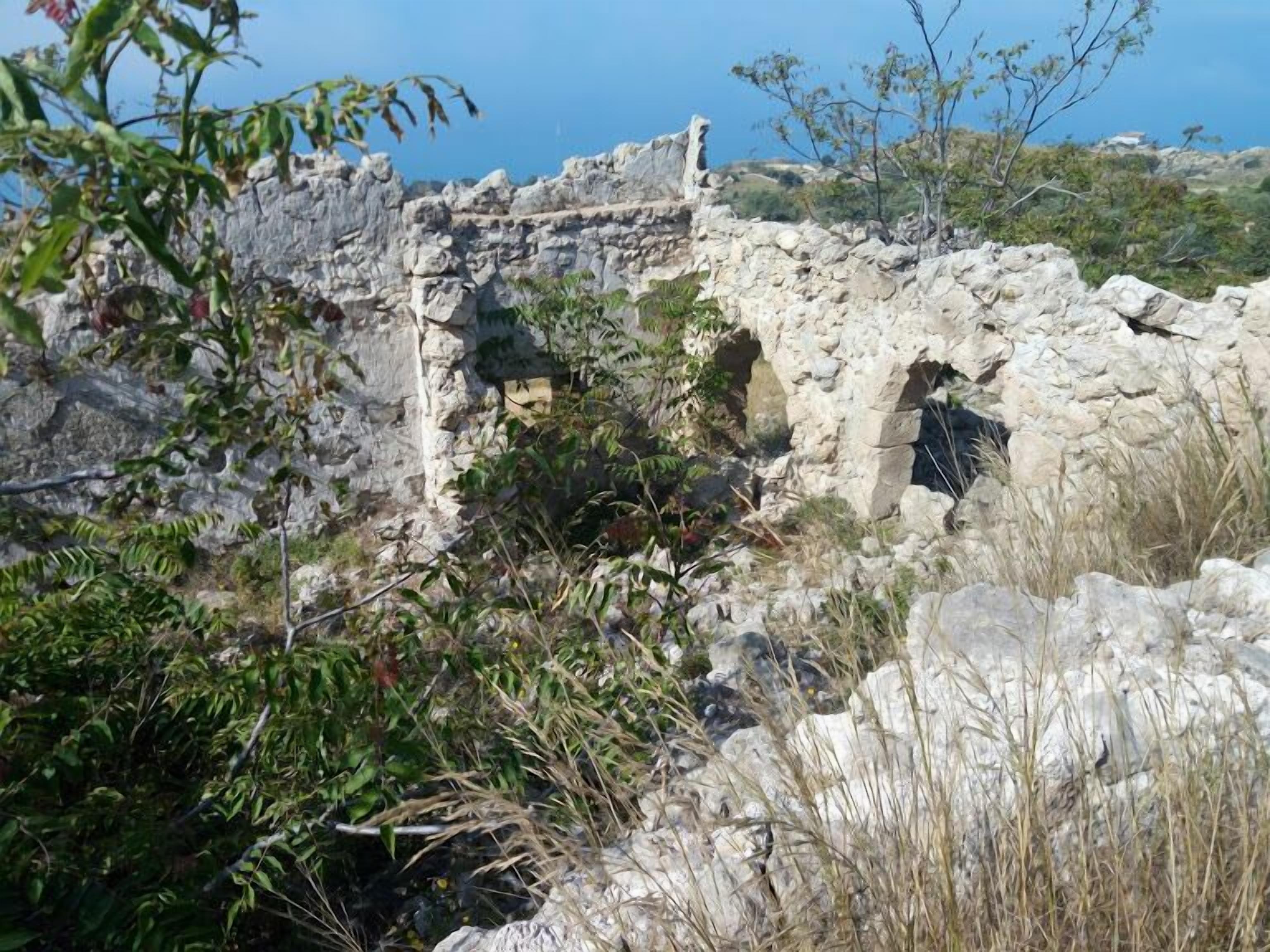 A stone wall with vegetation growing around it.