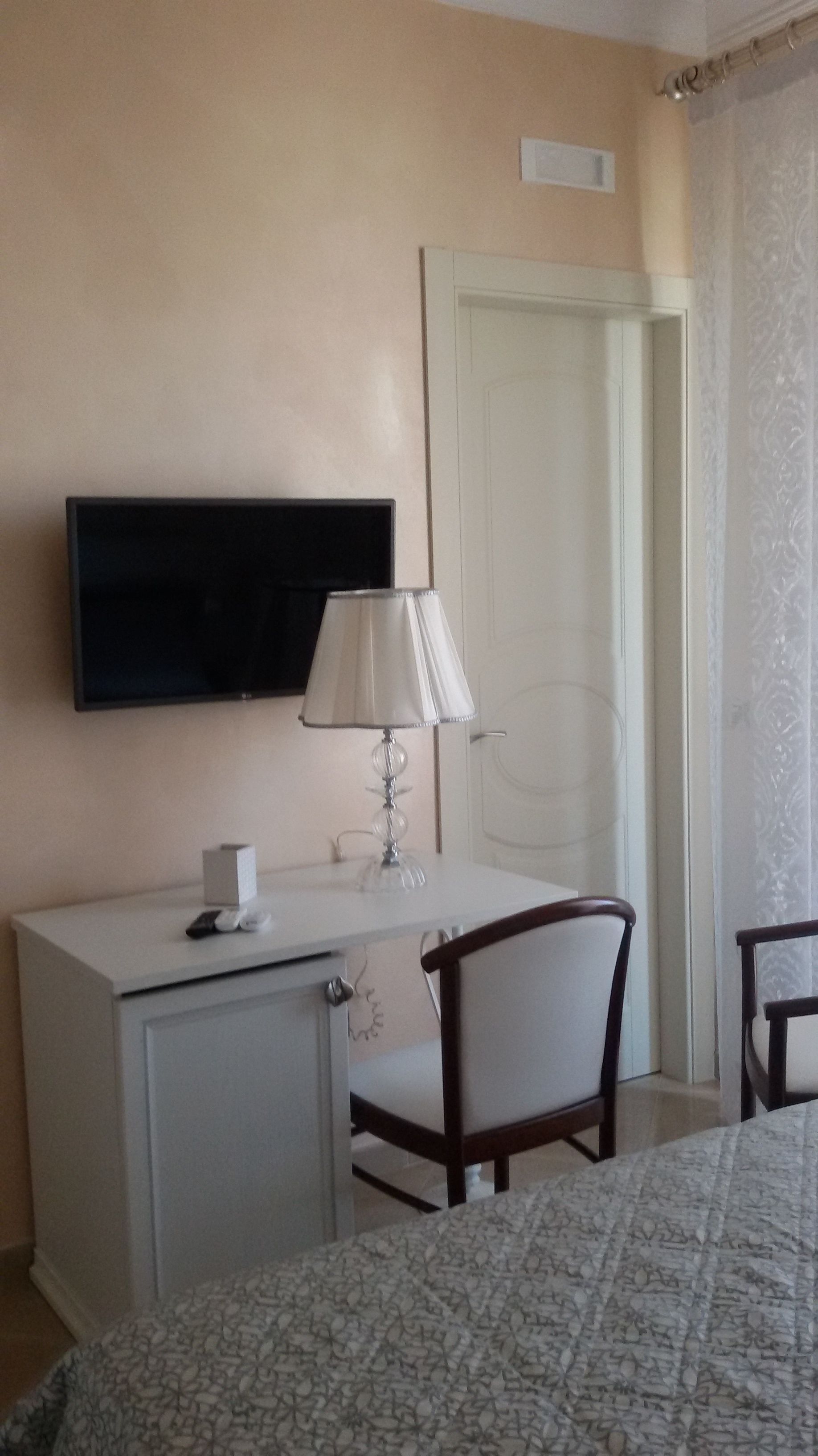 Une chambre d’hôtel avec un lit, un bureau doté d’une lampe, une télévision et une chaise.