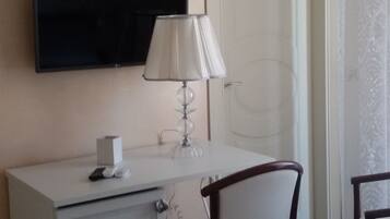 Une chambre d’hôtel avec un lit, un bureau doté d’une lampe, une télévision et une chaise.