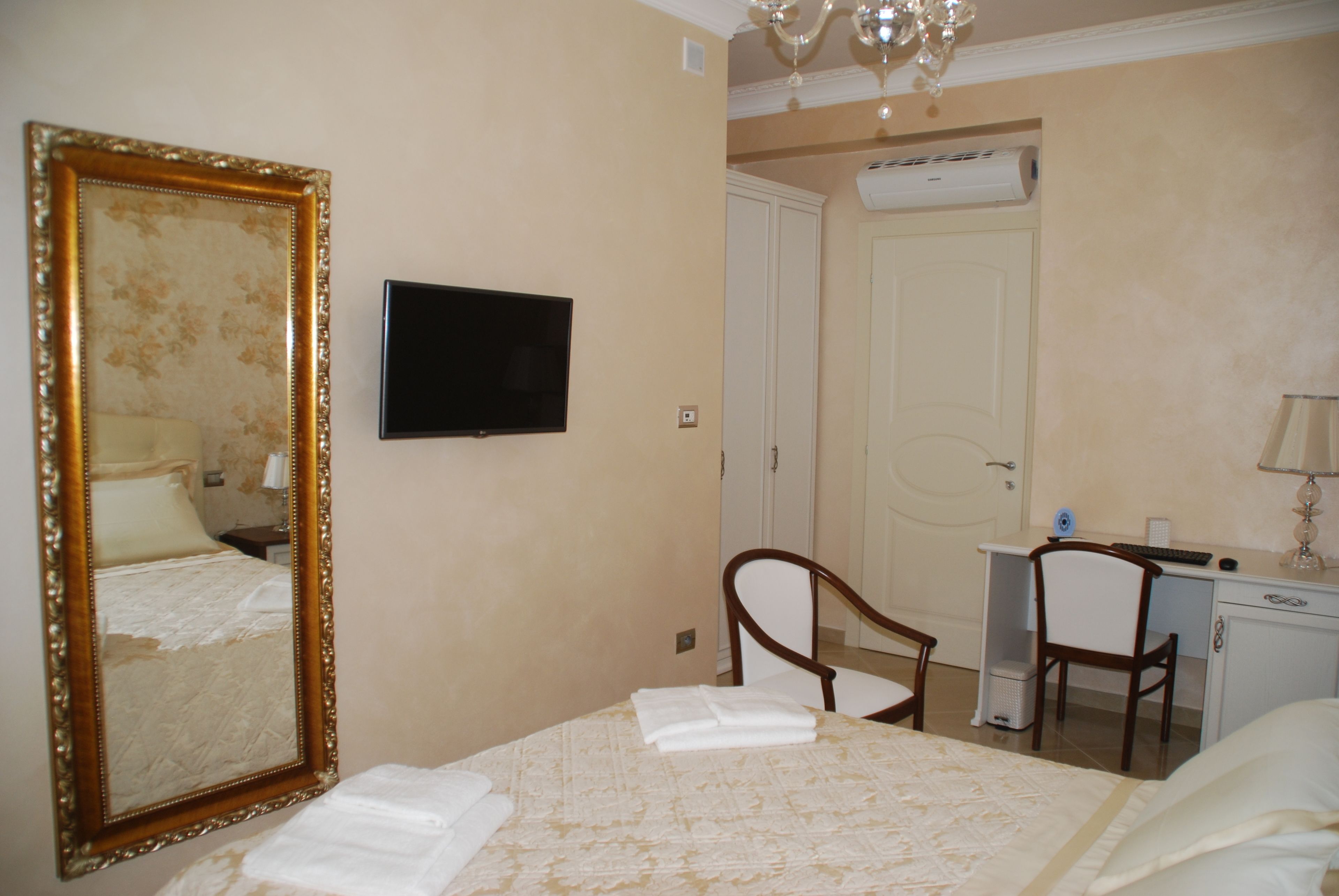 Une chambre d’hôtel avec un grand lit, un bureau avec une chaise, une télévision et une armoire.