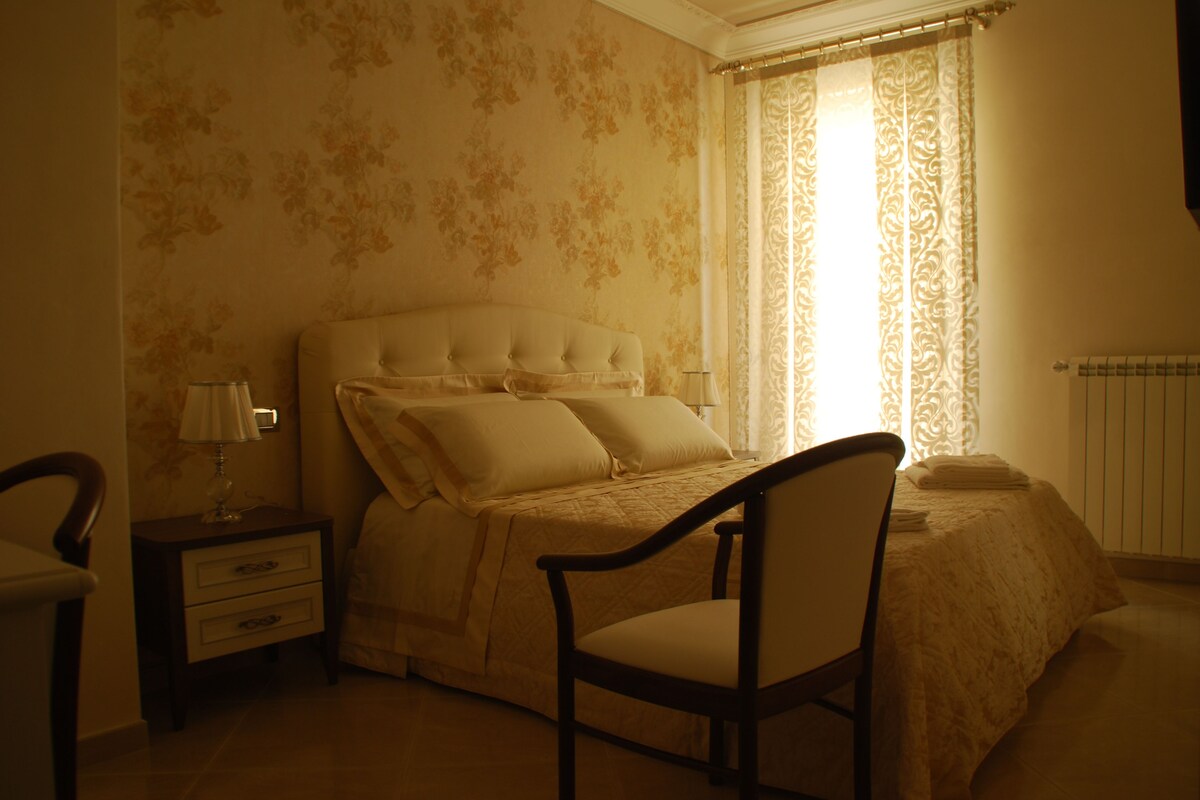 A bedroom with a bed, a chair, a nightstand, and a window with curtains.