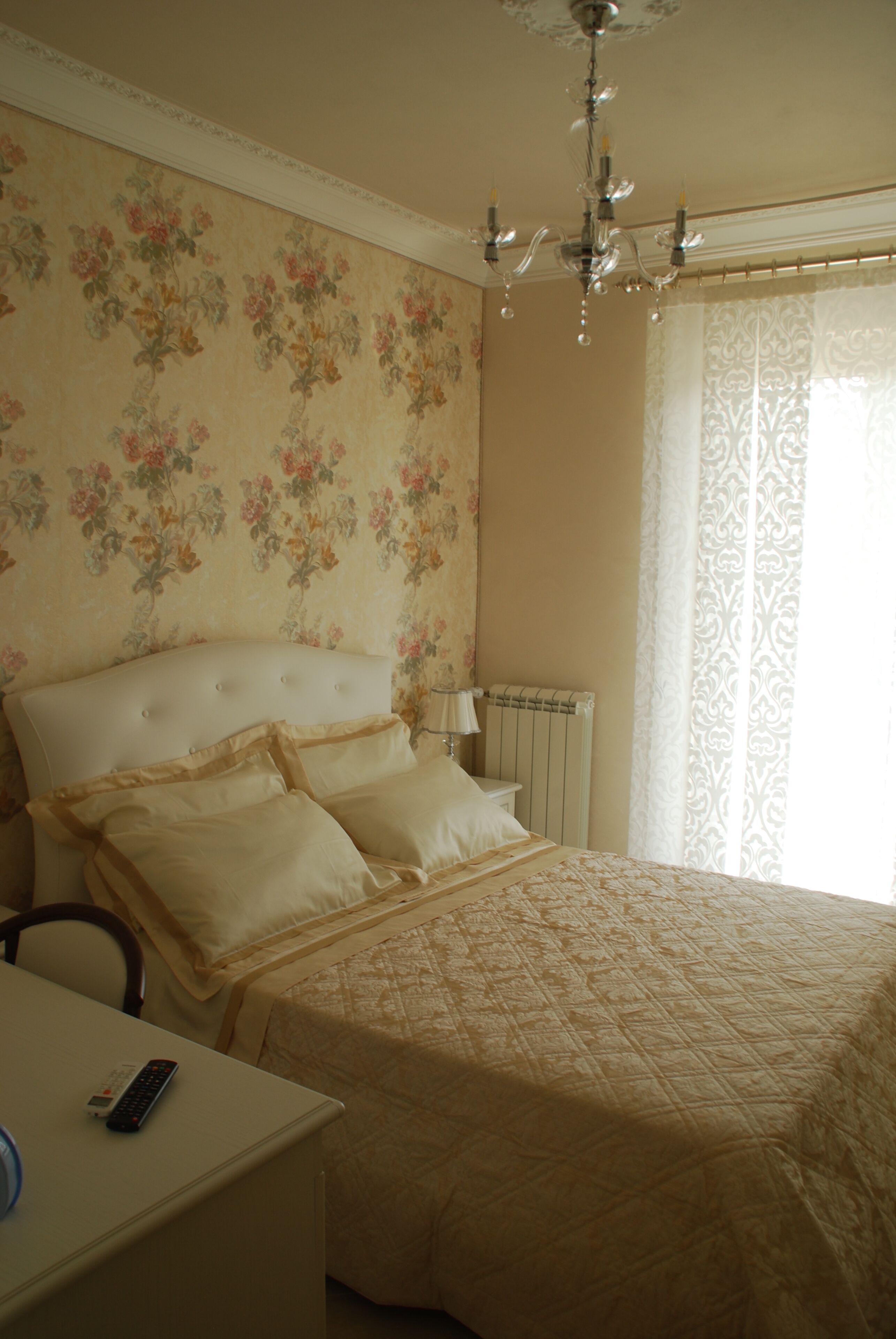Un dormitorio con cama, mesita de noche, control remoto y candelabro.