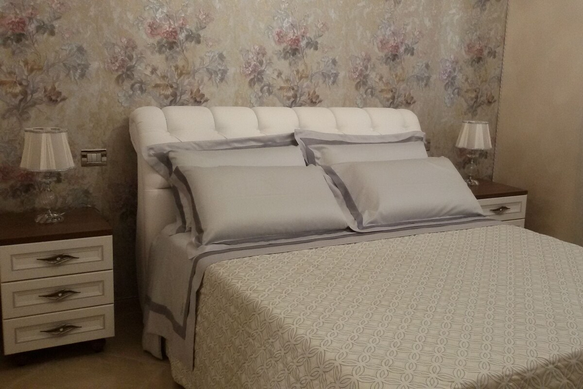 Un dormitorio con una cama, dos mesitas de noche y un papel tapiz floral.