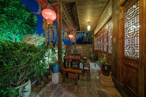 An indoor garden with wooden tables and benches, potted plants, and hanging red lanterns. - Yangshuo Mountain Nest Boutique Hotel (Guilin)